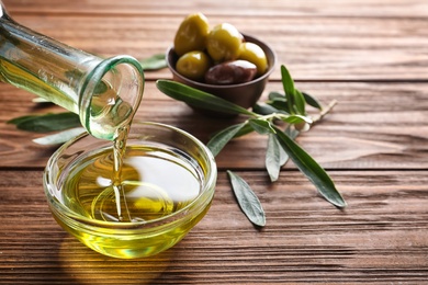 Pouring fresh olive oil into bowl on table