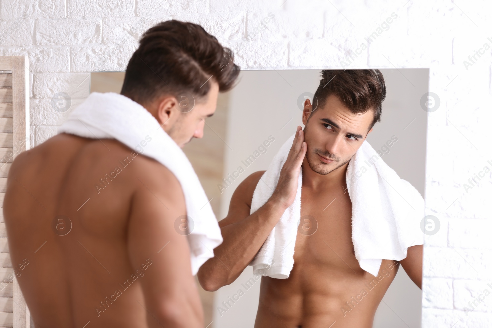 Photo of Young man with stubble ready for shaving near mirror in bathroom