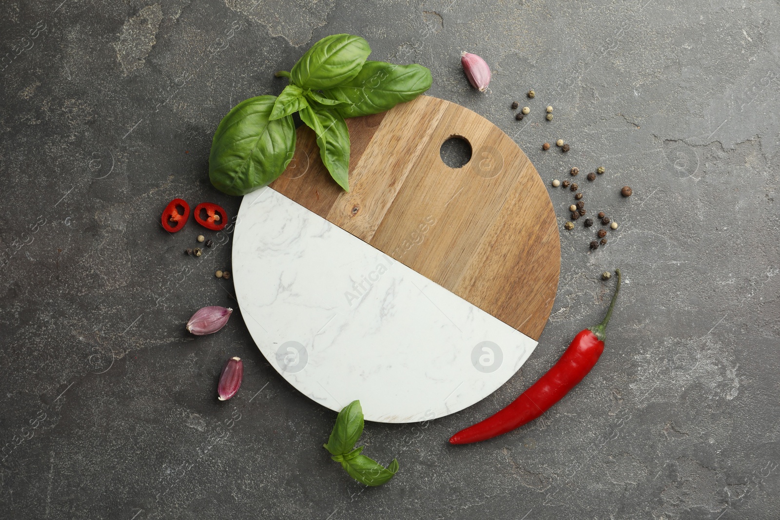 Photo of Cutting board, basil, pepper, chili peppers and garlic on grey table, flat lay. Space for text