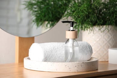 Tray with dispenser bottle and towel on wooden table