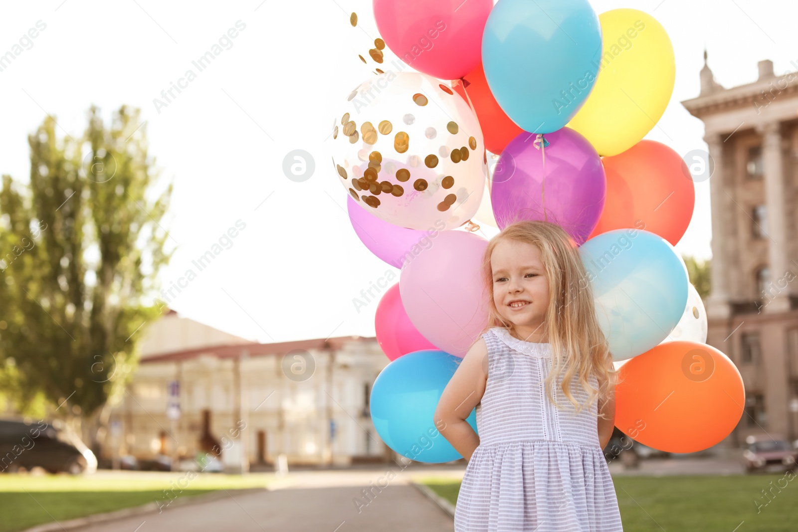 Photo of Cute little girl with colorful balloons outdoors on sunny day