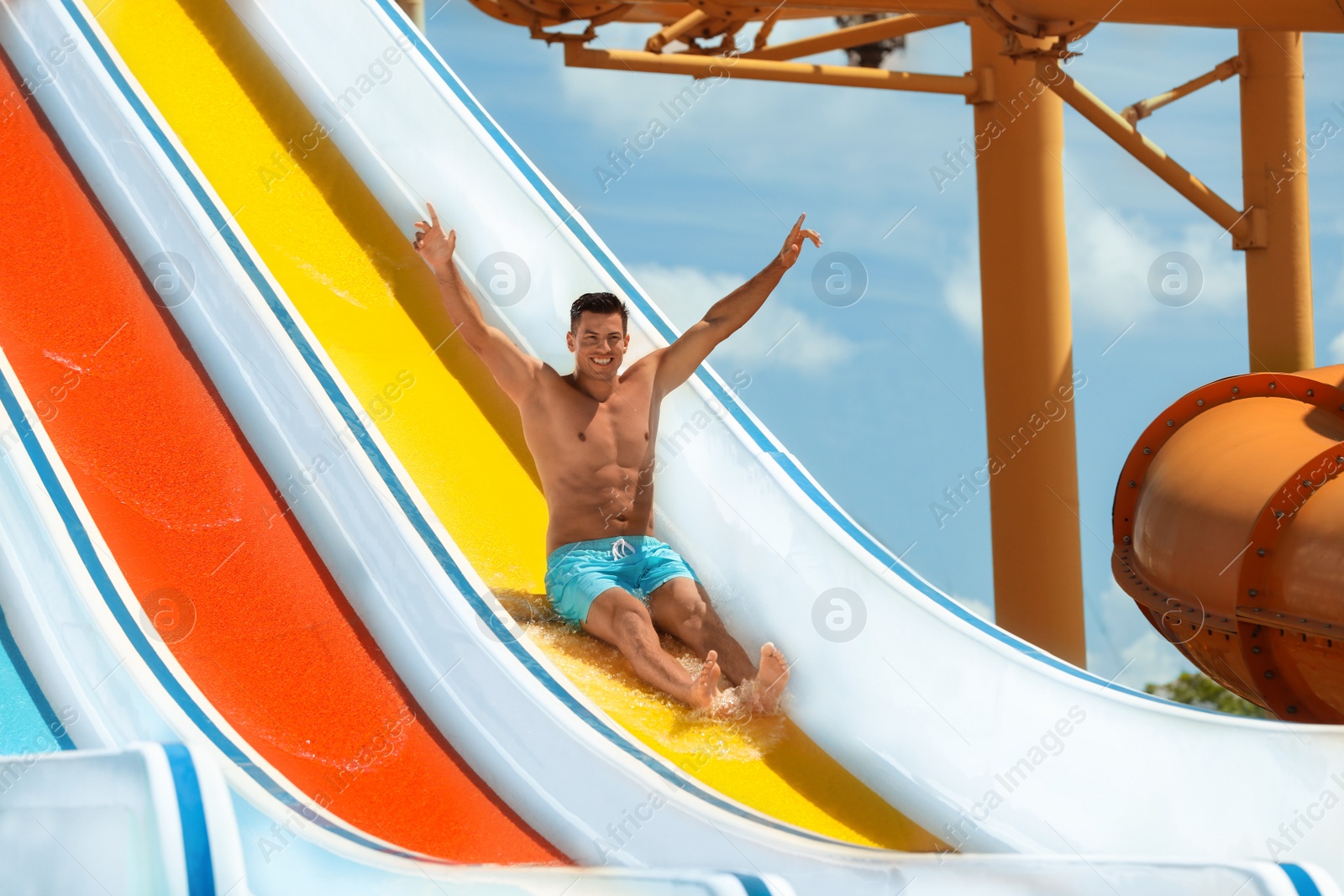 Photo of Man on slide at water park. Summer vacation