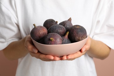 Photo of Woman holding bowl with tasty raw figs, closeup