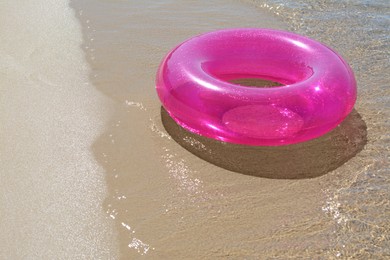Bright inflatable ring on sandy beach near sea. Space for text