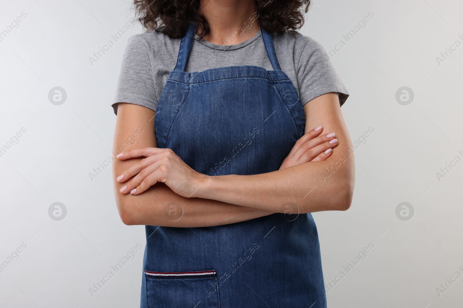 Photo of Woman wearing kitchen apron on light grey background, closeup. Mockup for design