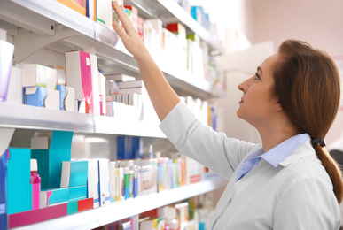 Image of Professional pharmacist near shelves with medicines in drugstore