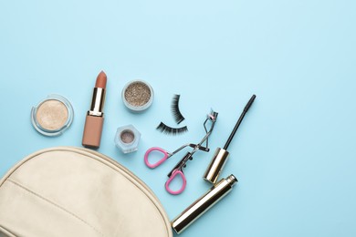 Photo of Eyelash curler, cosmetic bag and makeup products on light blue background, flat lay