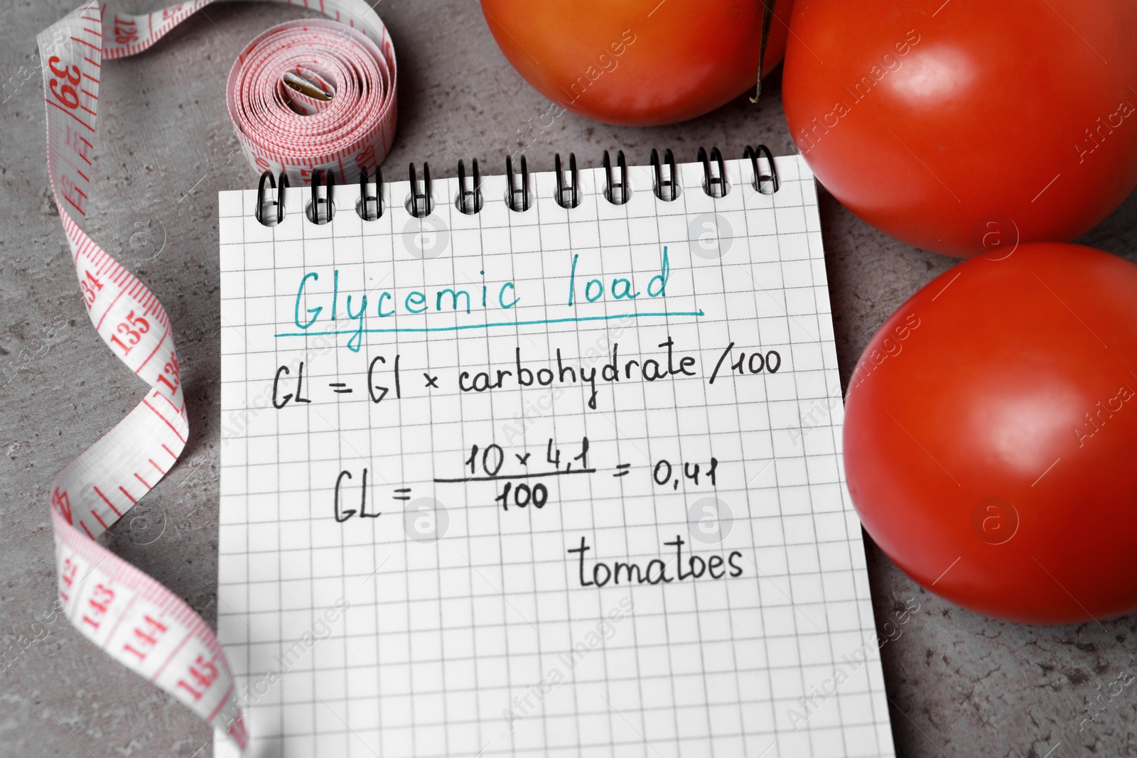 Photo of Notebook with calculated glycemic load for tomatoes, measuring tape and fresh vegetables on grey table, above view