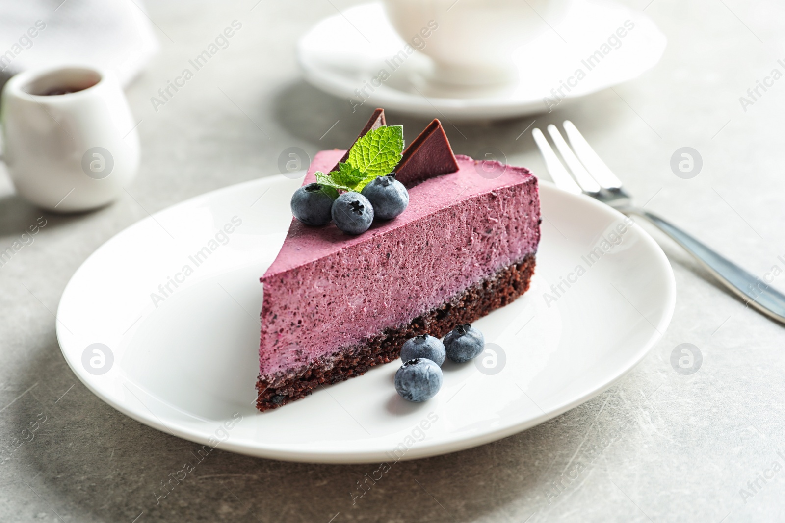 Photo of Plate with piece of tasty blueberry cake on gray table