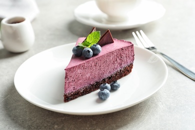 Photo of Plate with piece of tasty blueberry cake on gray table