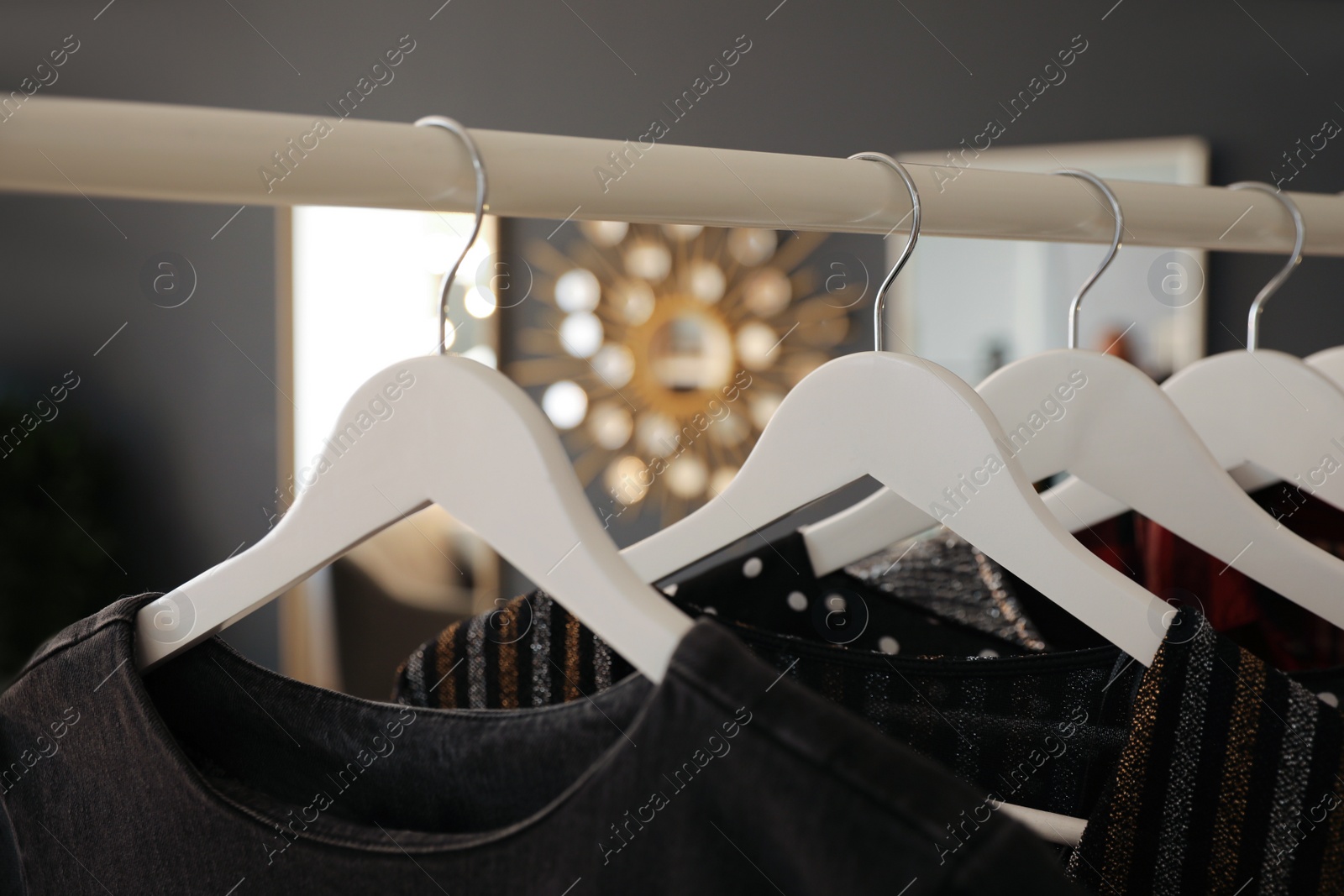 Photo of Collection of modern clothes hanging on rack indoors