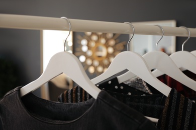 Collection of modern clothes hanging on rack indoors