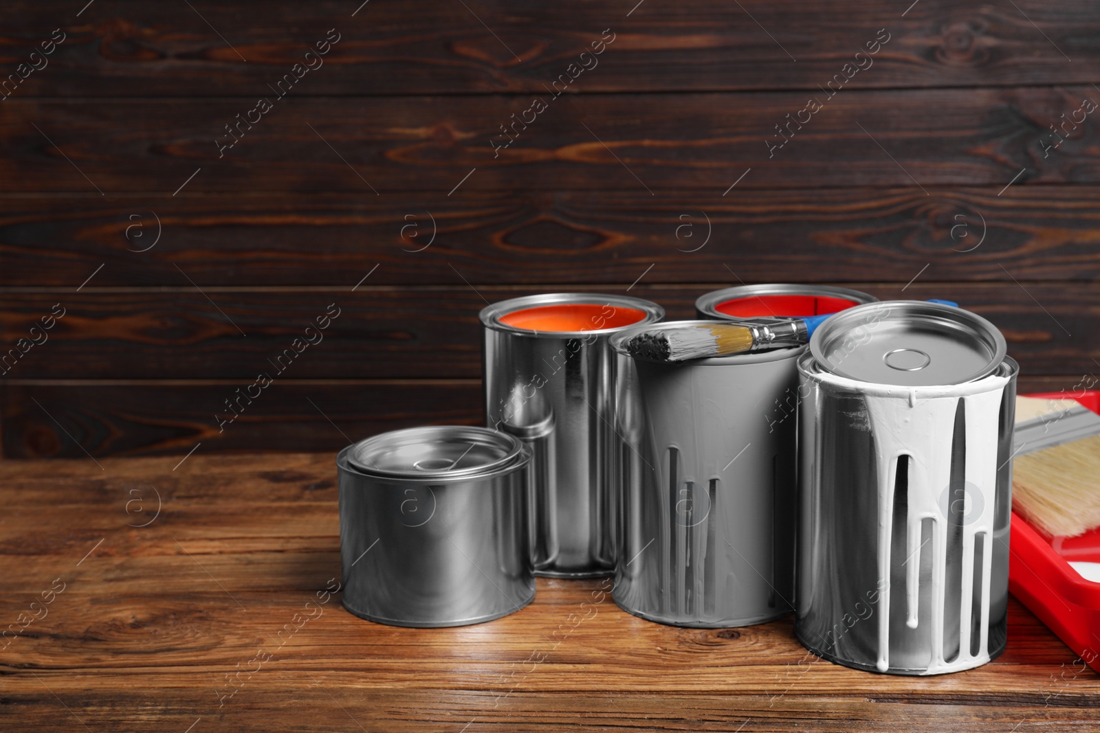 Photo of Cans of paints and brushes on wooden table. Space for text