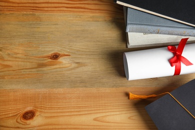 Flat lay composition with graduation hat and student's diploma on wooden table, space for text