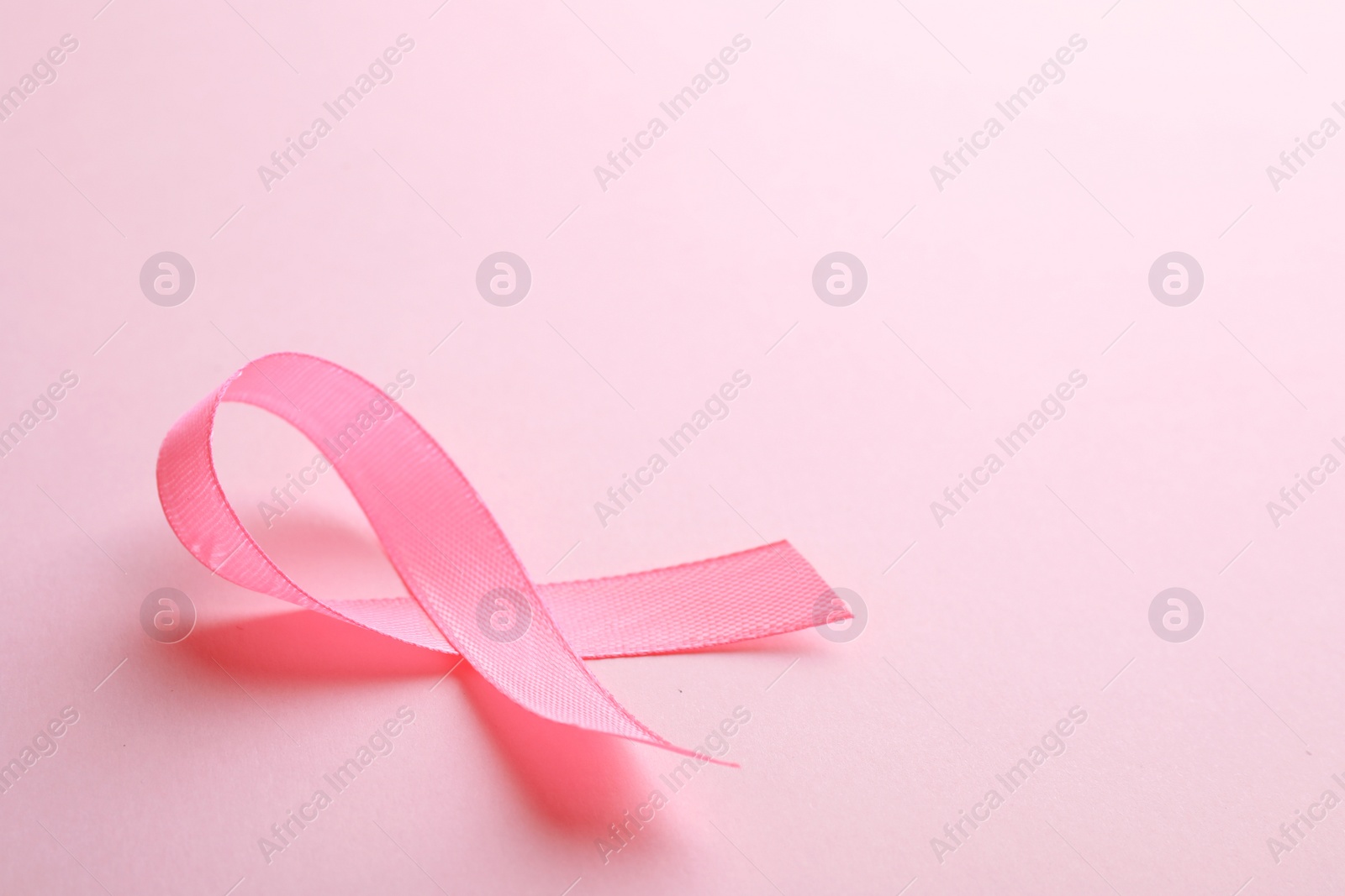 Photo of Pink ribbon on color background, space for text. Breast cancer awareness concept