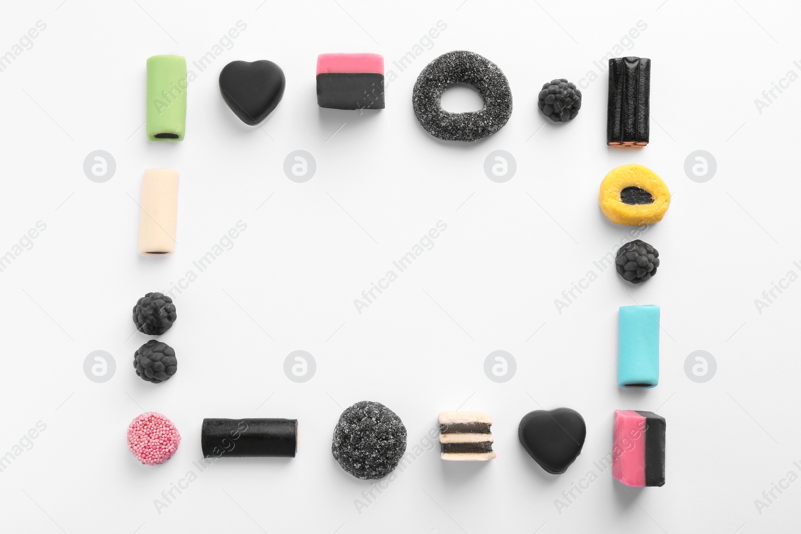 Photo of Frame made of tasty liquorice candies on light background, flat lay. Space for text