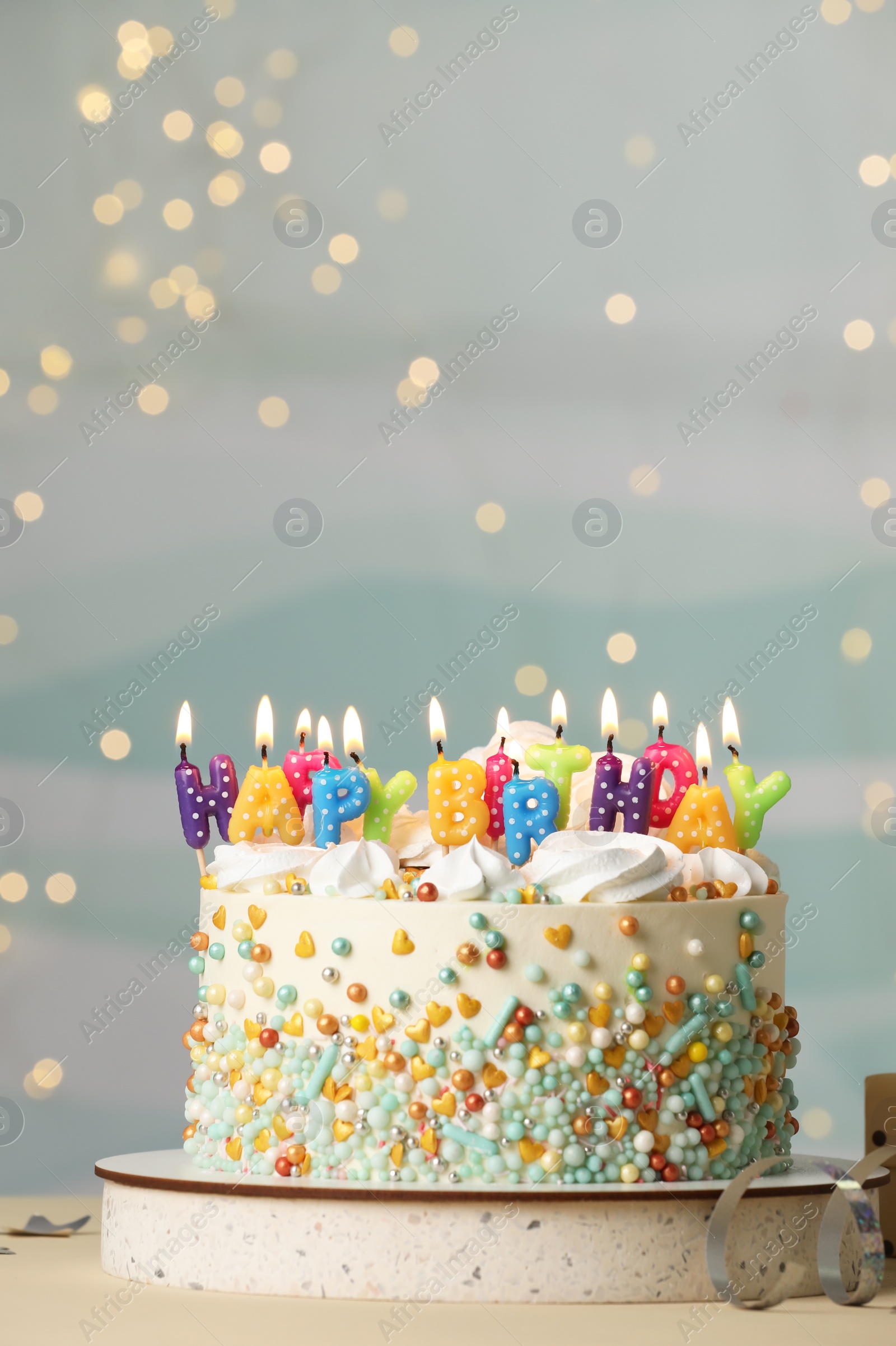 Photo of Beautiful birthday cake with burning candles and decor on white table