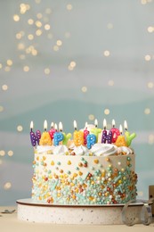 Photo of Beautiful birthday cake with burning candles and decor on white table