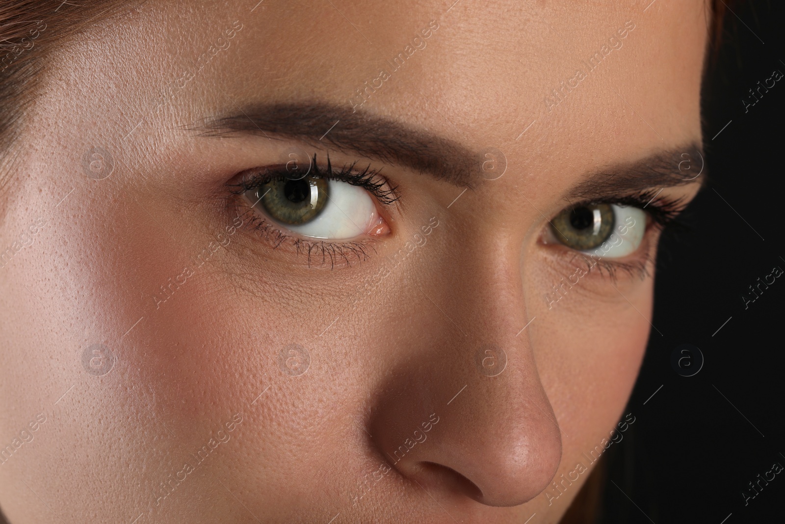 Photo of Evil eye. Young woman with scary eyes on black background, closeup