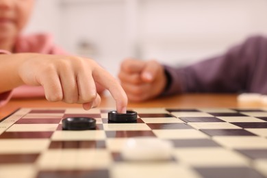 Photo of Girl playing checkers at table indoors, closeup