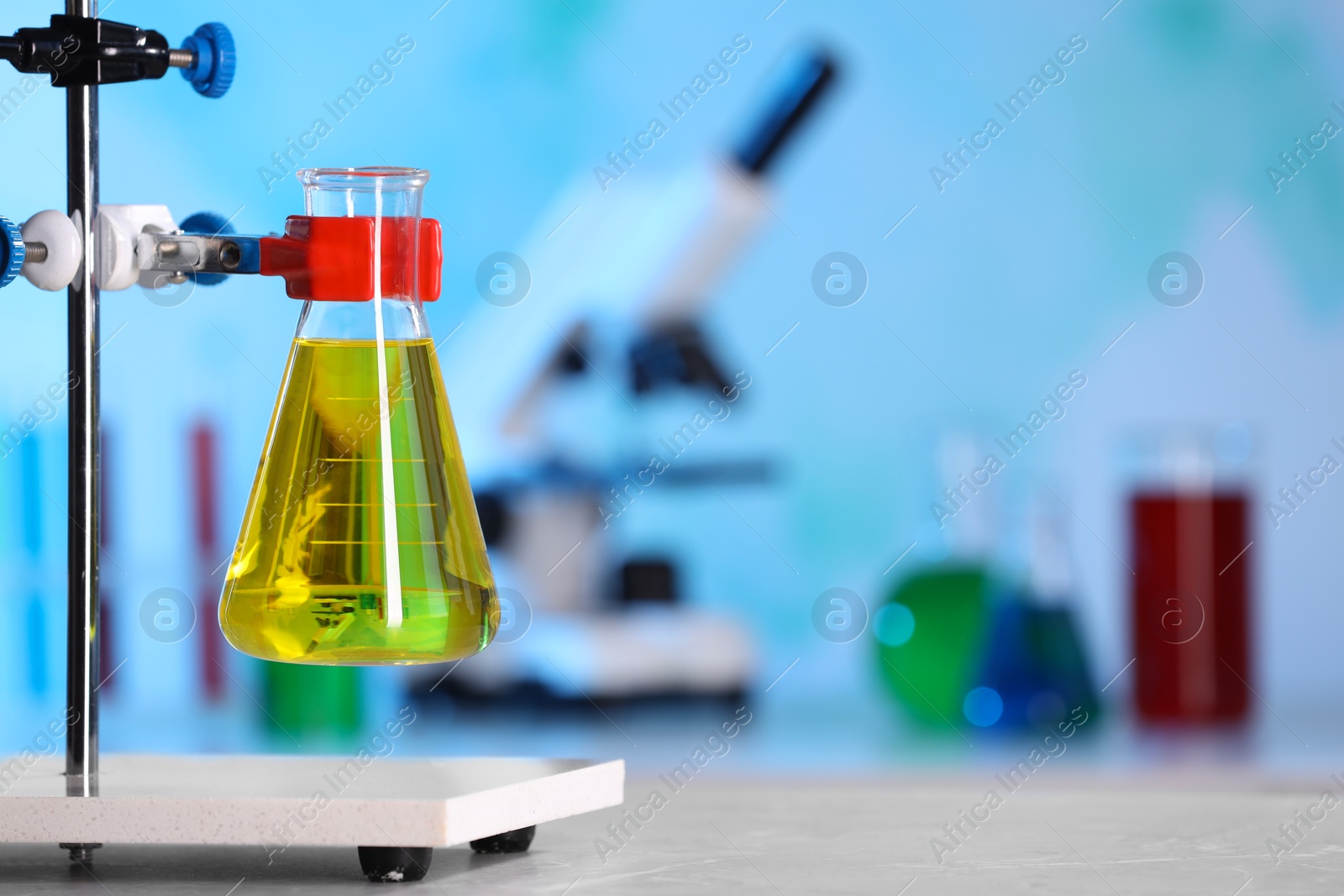 Photo of Flask with yellow liquid on retort stand in laboratory. Space for text