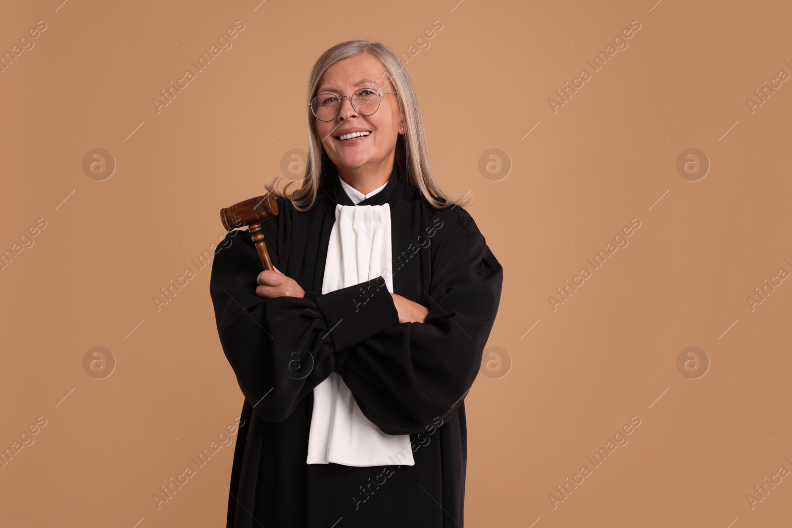 Photo of Smiling senior judge with gavel on light brown background