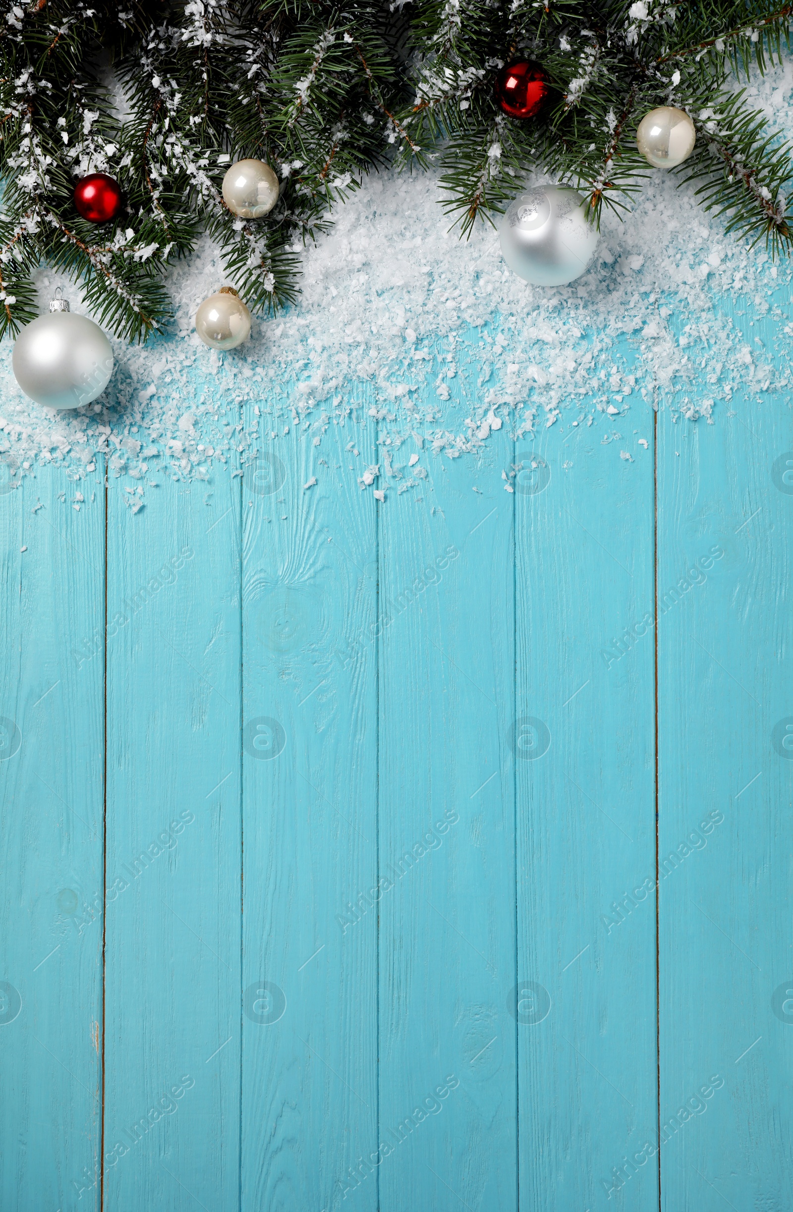 Photo of Christmas decoration with white snow on light blue wooden background, flat lay. Space for text