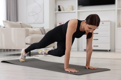 Photo of Morning routine. Woman doing abs exercise at home