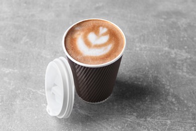 Photo of Coffee to go. Paper cup with tasty drink on grey table