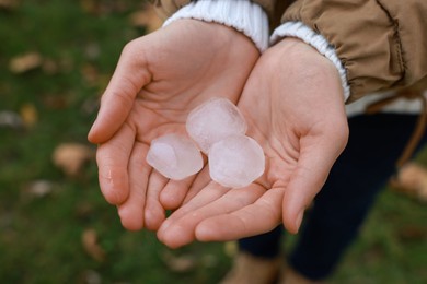 Photo of Woman holding hail grains after thunderstorm outdoors, closeup