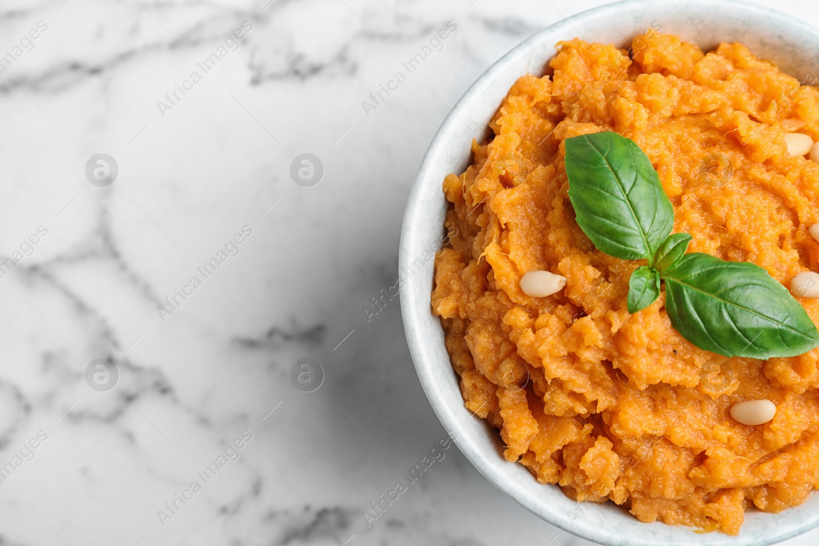 Photo of Bowl of tasty sweet potato puree on marble table, top view. Space for text