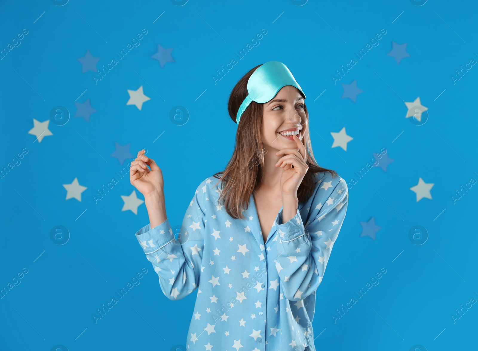 Photo of Beautiful woman wearing pajamas and sleep mask on light blue background. Bedtime