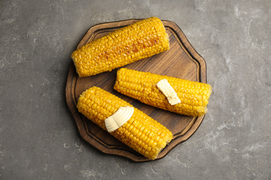 Delicious grilled corn with butter on grey table, top view