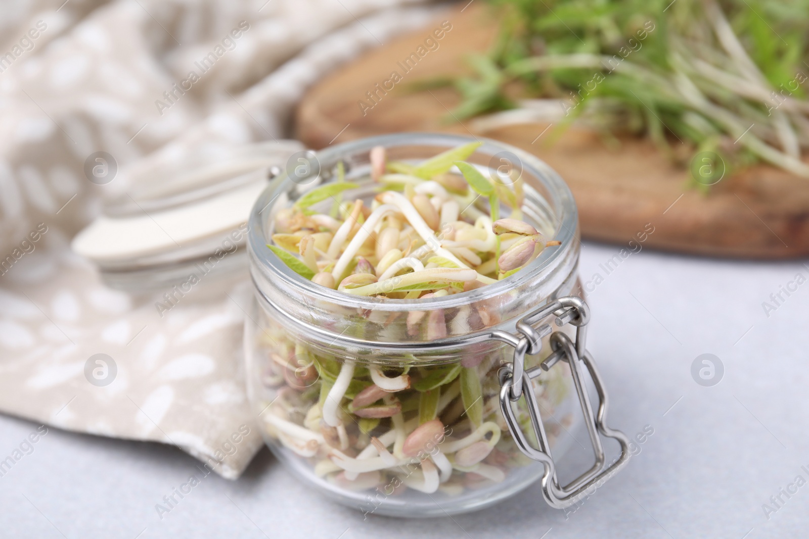 Photo of Mung bean sprouts in glass jar on white table, closeup