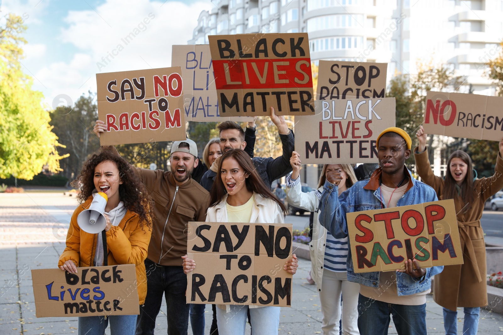 Photo of Protesters demonstrating different anti racism slogans outdoors. People holding signs with phrases