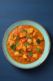 Photo of Delicious chicken curry on blue wooden table, top view