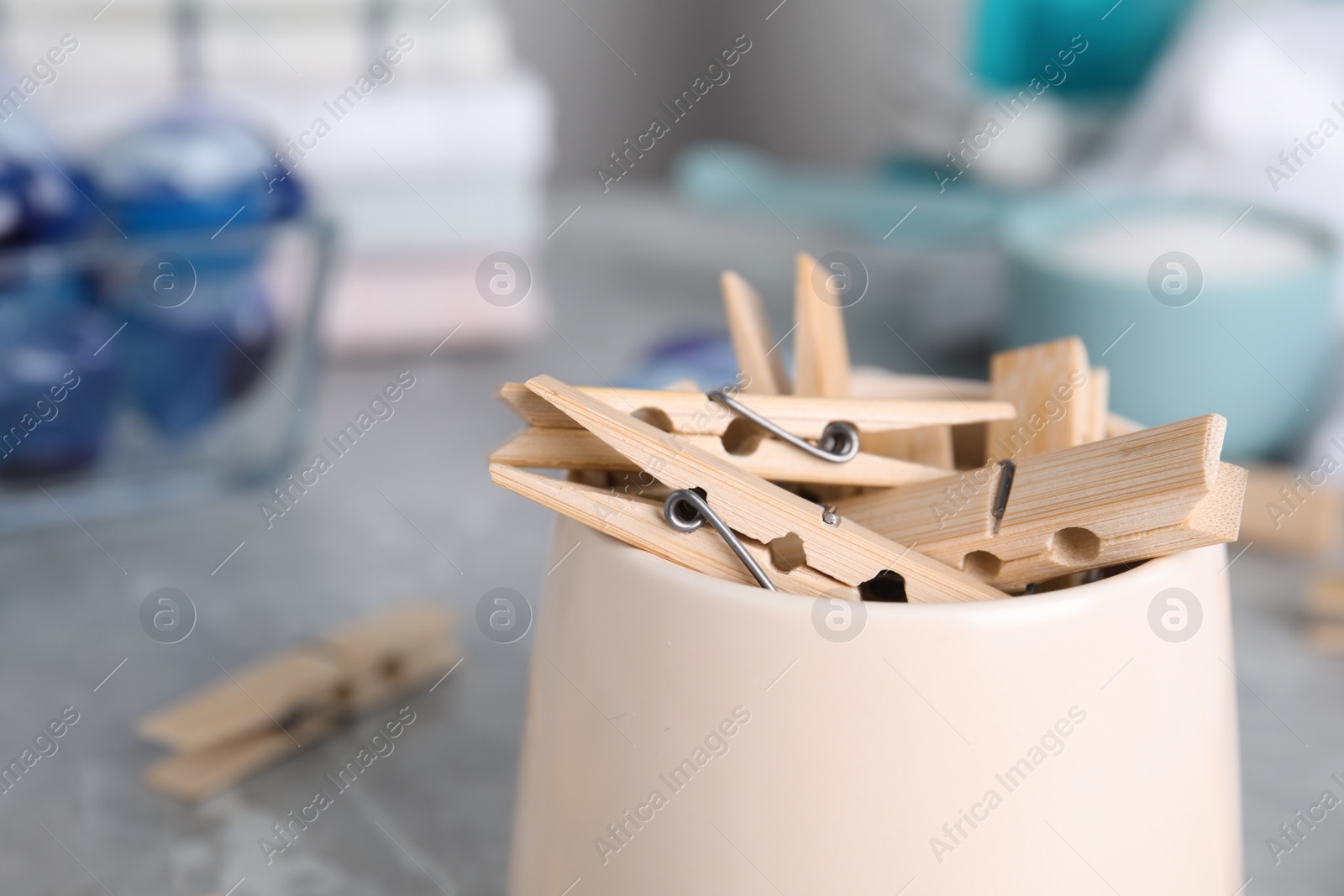 Photo of Many wooden clothespins in cup on table, closeup. Space for text