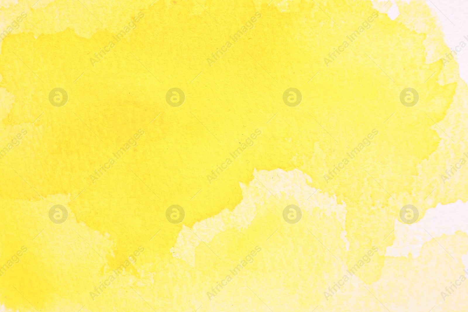 Photo of Abstract yellow watercolor painting on white paper, top view