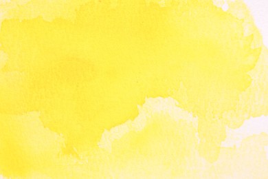 Photo of Abstract yellow watercolor painting on white paper, top view