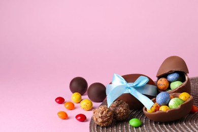 Tasty chocolate eggs and candies on pink background. Space for text