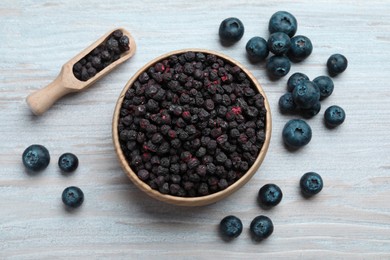 Photo of Freeze dried and fresh blueberries on white wooden table, flat lay