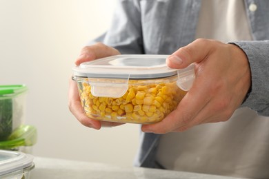 Photo of Man holding glass container with tasty corn kernels, closeup. Food storage
