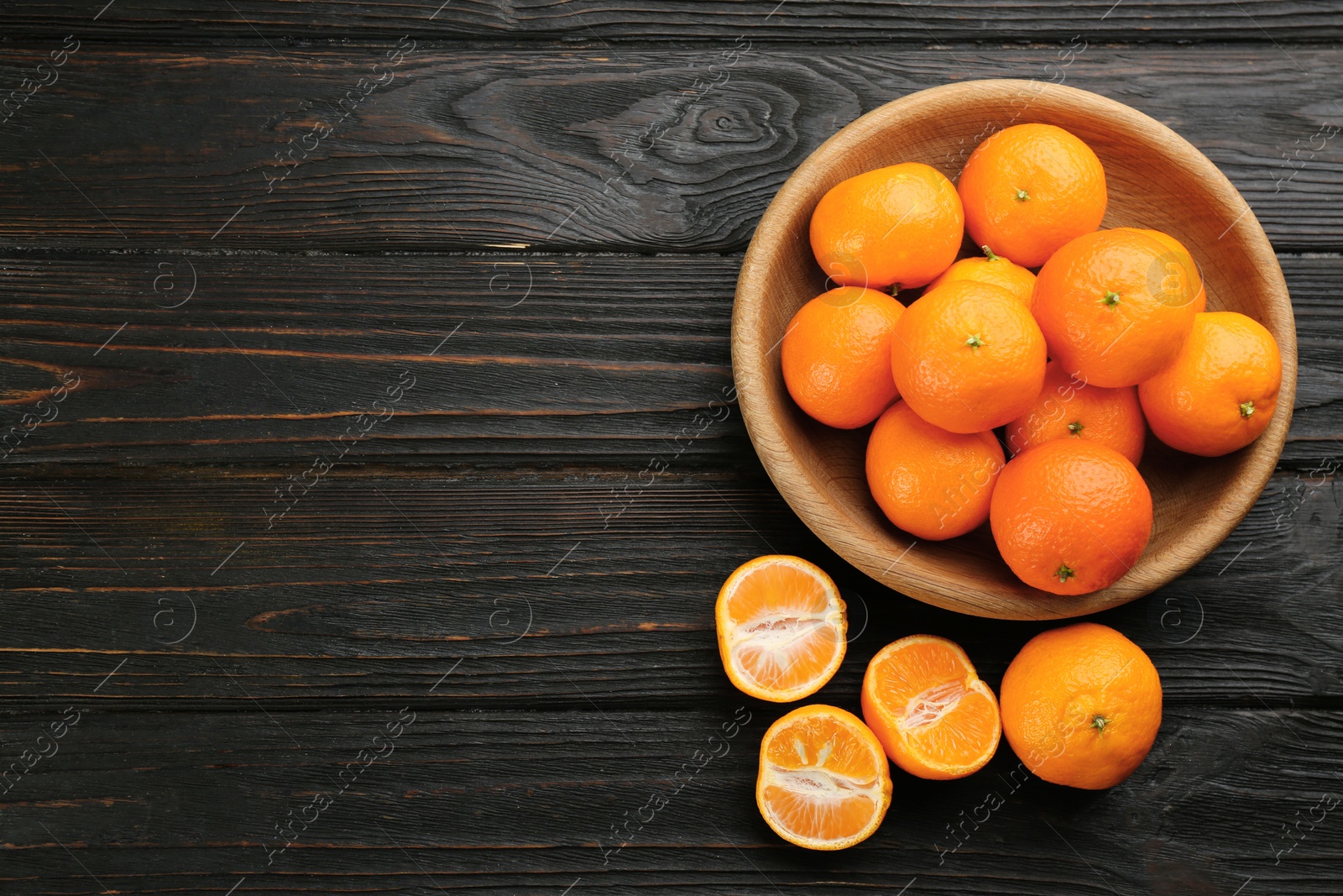 Photo of Fresh ripe tangerines on black wooden table, flat lay. Space for text