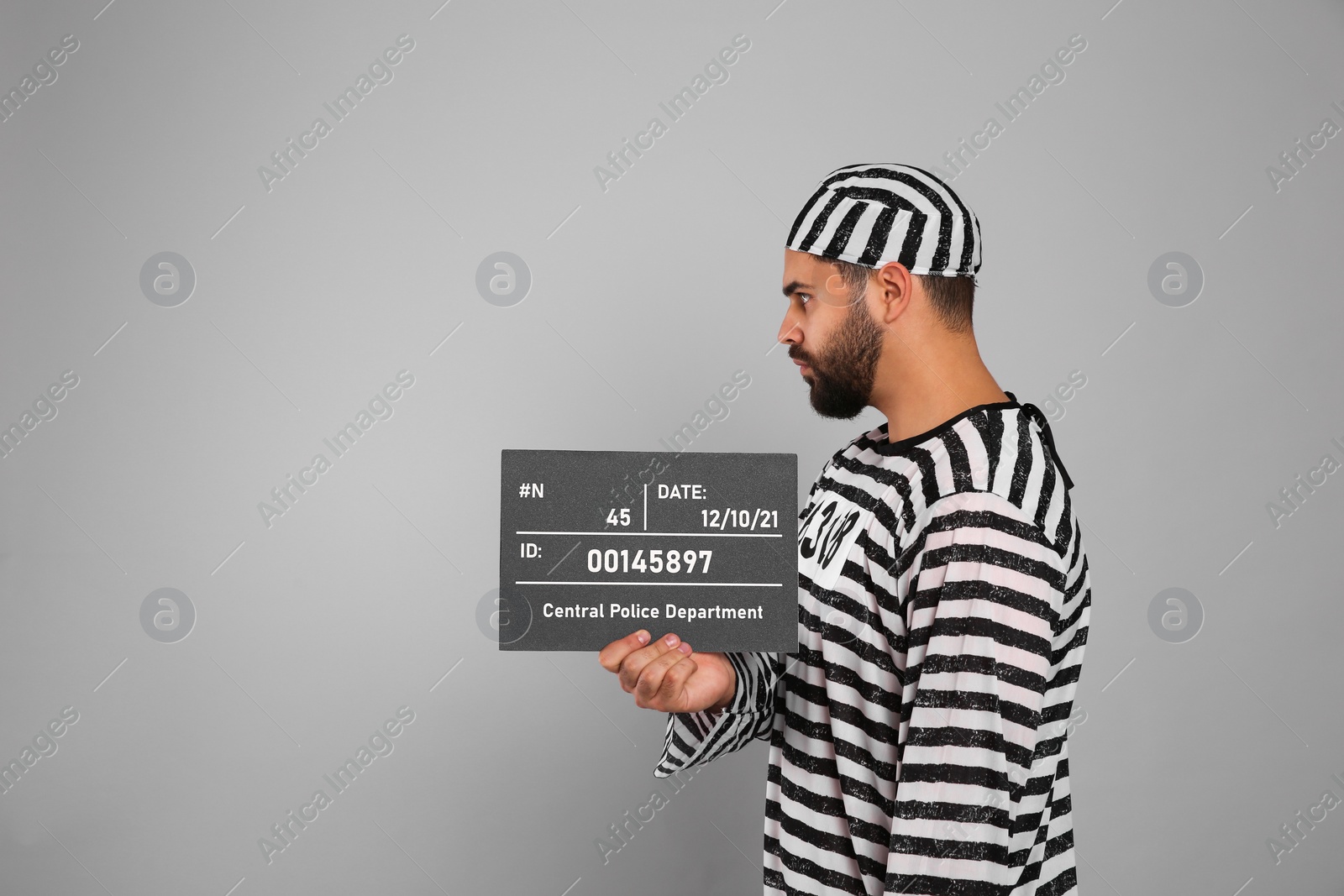 Photo of Prisoner in special uniform with mugshot letter board on grey background, space for text