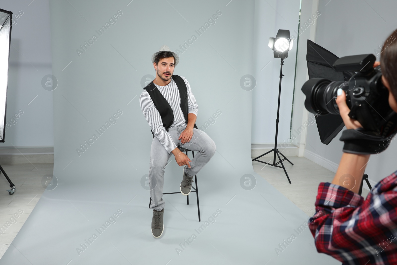 Photo of Professional photographer taking picture of young man in modern studio