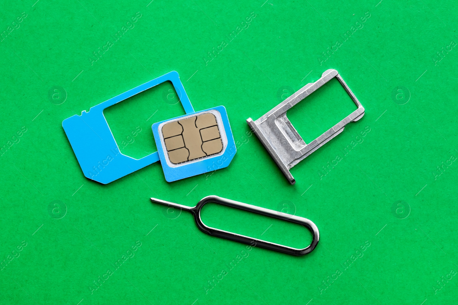 Photo of SIM card, tray and ejector on green background, flat lay