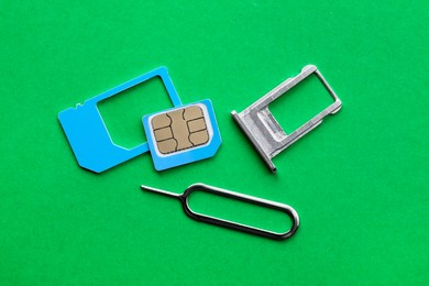 SIM card, tray and ejector on green background, flat lay