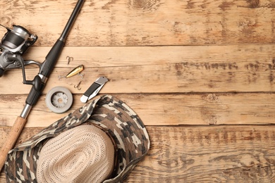 Photo of Flat lay composition with fishing equipment and space for text on wooden background