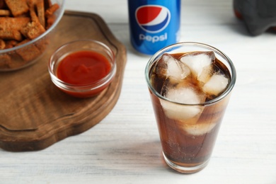 MYKOLAIV, UKRAINE - FEBRUARY 15, 2021: Glass of Pepsi on white wooden table