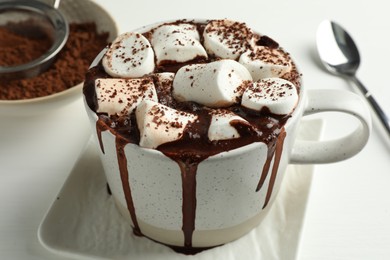 Photo of Delicious hot chocolate with marshmallows and cocoa powder in cup on white table, closeup